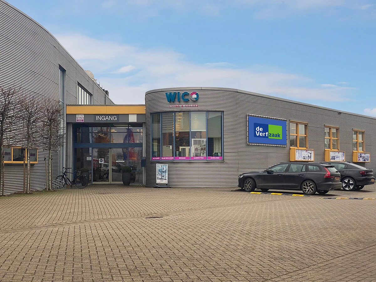 De Verfzaak Nijmegen — Winkelfront met blauwe bord en parkeerplaats