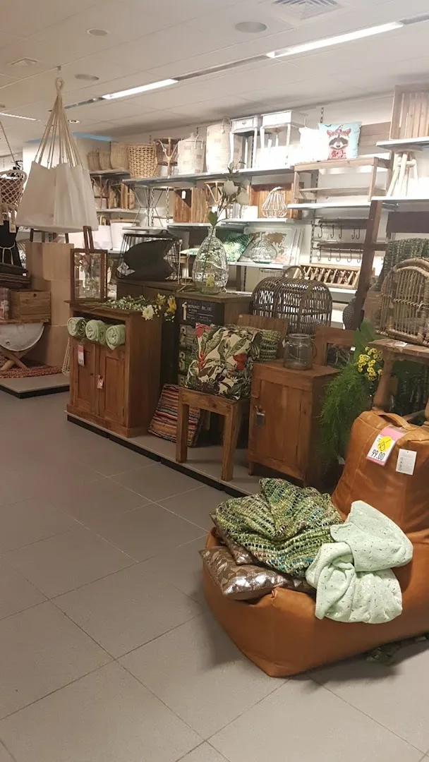 Xenos Lelystad — Winkelhoek met houten meubels en plantenpotten